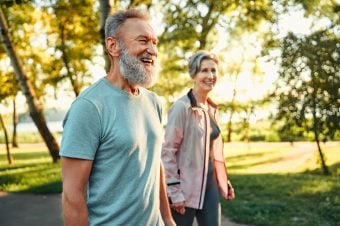 Elderly couple walking in the park in sunny weather.